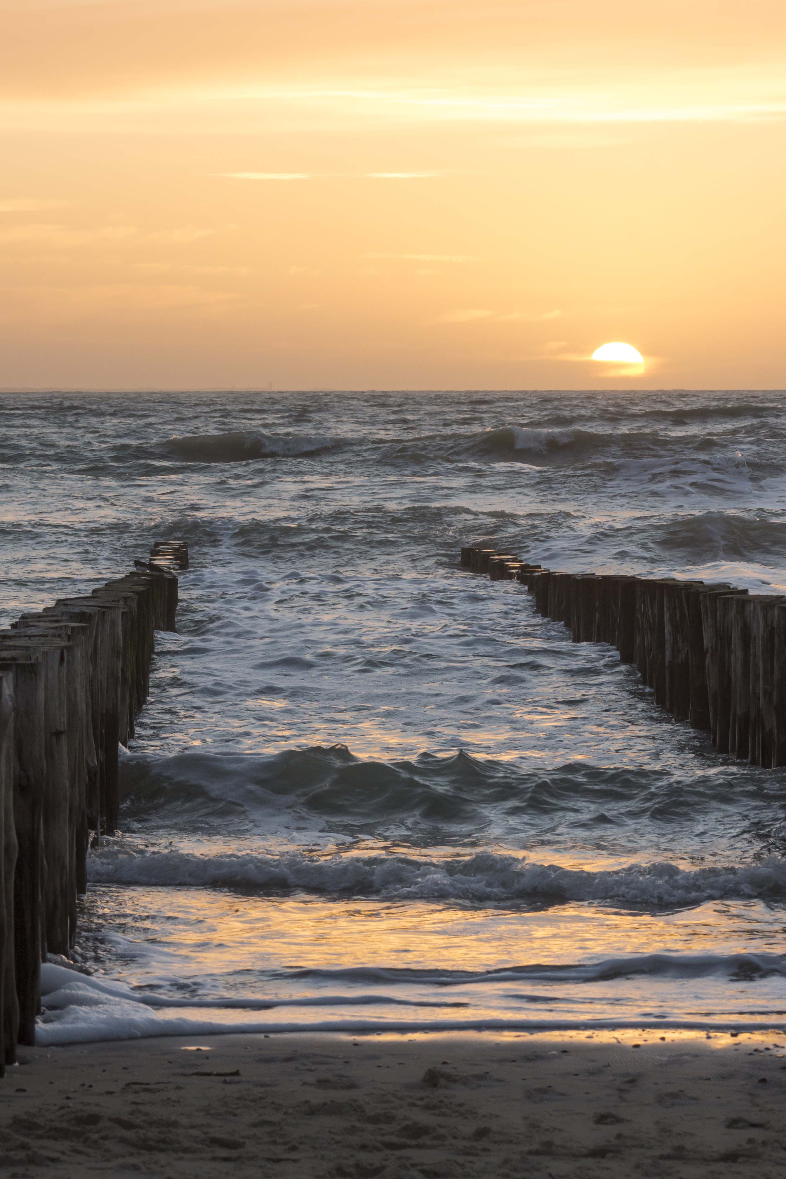 paalhoofd en ondergaande zon